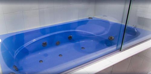 a blue tub in a bathroom with a glass wall at Hotel Xilon Resort Pasto in Pasto