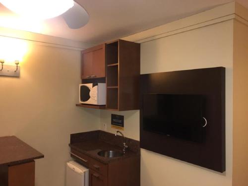 a small kitchen with a sink and a tv at Flat em Gramado in Gramado