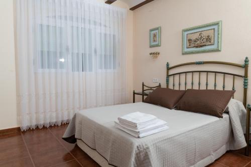 a bedroom with a bed with white sheets and a window at Casa Rural Doña Josefa in Cilanco
