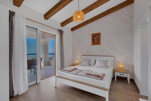 a white bedroom with a bed and a balcony at NEW! Milan's House with pool, Mediterranean in Makarska