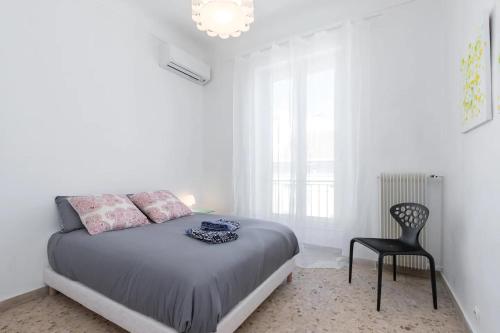 une chambre blanche avec un lit et une chaise dans l'établissement FEEL HOME - ASSALIT, à Nice