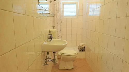 a white bathroom with a toilet and a sink at 35 meters from sea Apartment Keser and House for rent in Karlobag