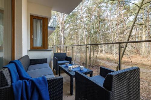 a porch with chairs and tables and a view of the woods at Fabulous Apartments - Euronia in Pobierowo
