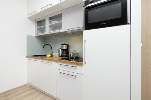 a kitchen with white cabinets and a microwave at Fabulous Apartments - Euronia in Pobierowo