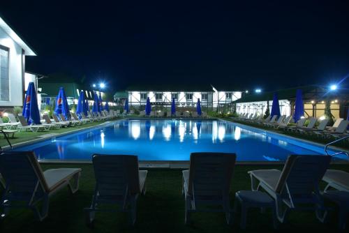 a swimming pool at night with chairs and umbrellas at Hotel Lubenska Sloboda in Vilʼshanka