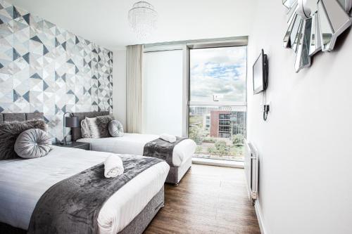 een slaapkamer met 2 bedden en een groot raam bij 2 Bedroom 2 Bathroom Apartment in Central Milton Keynes with Free Parking - Contractors, Relocation, Business Travellers in Milton Keynes