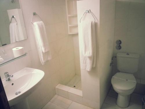 a white bathroom with a toilet and a sink at Natassa Hotel in Xanthi