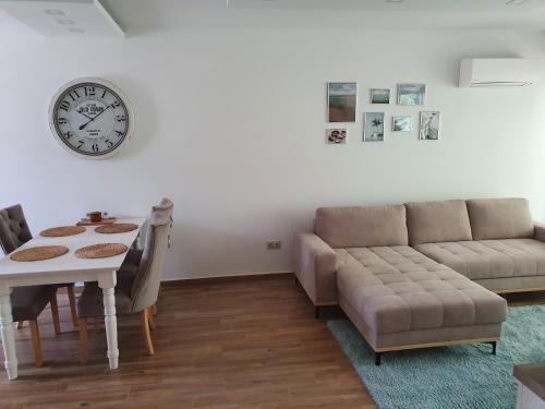a living room with a couch and a table and a clock at Sunshine Resort Turquoise Apartman in Zamárdi