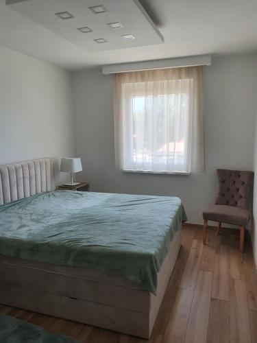 een slaapkamer met een bed, een stoel en een raam bij Sunshine Resort Turquoise Apartman in Zamárdi