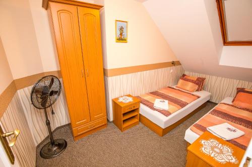 a small room with two beds and a fan at Tinódi Fogadó in Sárvár