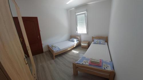 Cette petite chambre comprend 2 lits et une fenêtre. dans l'établissement Apartman G 60, à Meljine