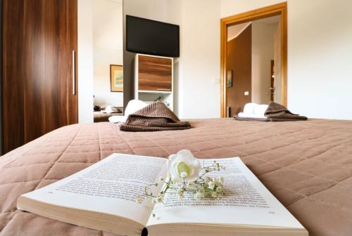 a book on a bed with a bouquet of flowers on it at AS Apartmani "Chocolate" in Peroj