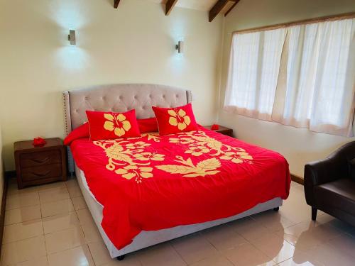 a bedroom with a red bed with red pillows at Tavake Villa in Arutanga