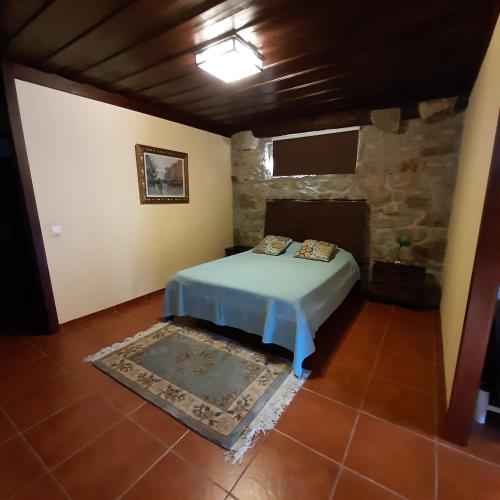 a bedroom with a bed and a stone wall at Quinta do Real - Casa de Campo in Viana do Castelo
