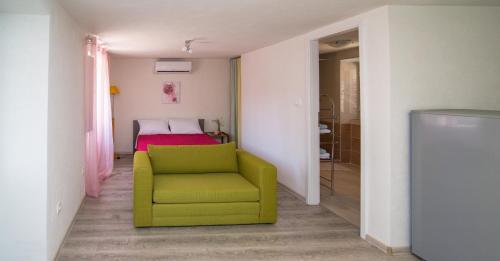 une chaise verte dans une chambre avec un lit dans l'établissement By Dinka, à Ilovik