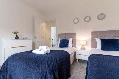 a bedroom with two beds with blue and white sheets at KVM Bluebird House for large groups by KVM Serviced Accommodation in Peterborough
