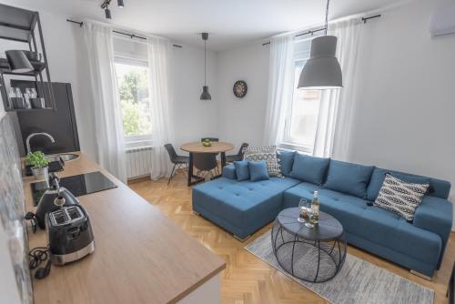 a living room with a blue couch and a table at Vila Pobeda in Banja Koviljača