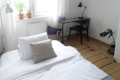 Una cama blanca con almohadas y un escritorio en una habitación. en ŚWIETNA LOKALIZACJA!!, en Olsztyn