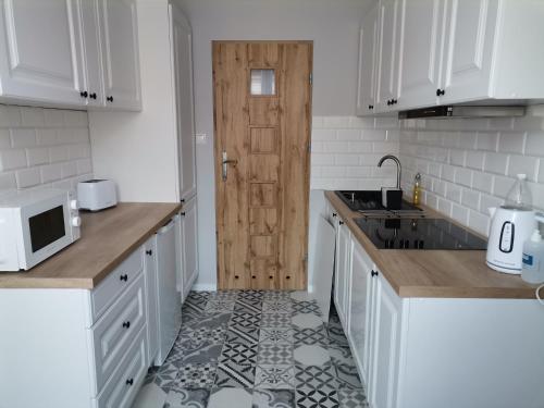 a kitchen with white cabinets and a wooden door at Apartament w ścisłym centrum miasta. in Lublin