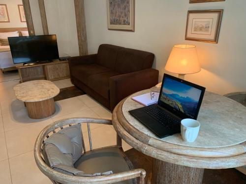 uma sala de estar com uma mesa com um computador portátil em LANDMARK By Hotelaria Brasil em São Paulo