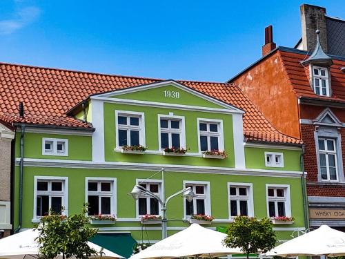 a green building with white windows and a red roof at AnaCapri Gästehaus Venezia in Ueckermünde