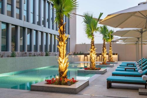 Park Inn by Radisson, Riyadh في الرياض: مسبح الفندق مع كراسي الصالة والمظلات