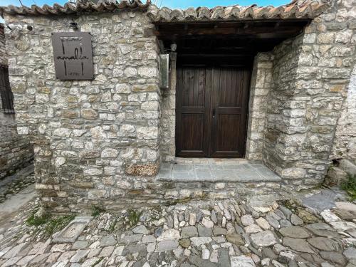 a stone building with a wooden door with a sign on it at Amalia Hotel in Berat