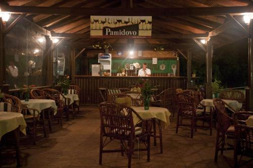 a restaurant with tables and chairs and a man standing in the background at Hotel Varshava in Golden Sands