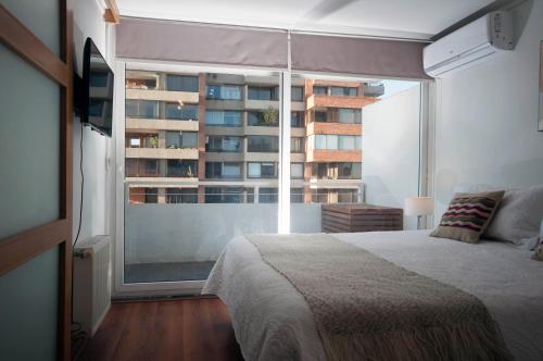 a bedroom with a bed and a large window at Las Condes, Excelentes Apartamentos - Sofia Camilla Propiedades in Santiago