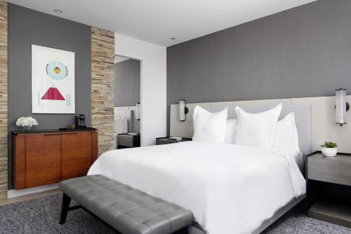 a bedroom with a large white bed and a bench at Four Seasons Hotel Denver in Denver