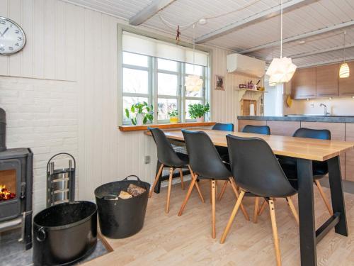 ein Esszimmer mit einem Tisch, Stühlen und einem Kamin in der Unterkunft 6 person holiday home in Ulfborg in Ulfborg
