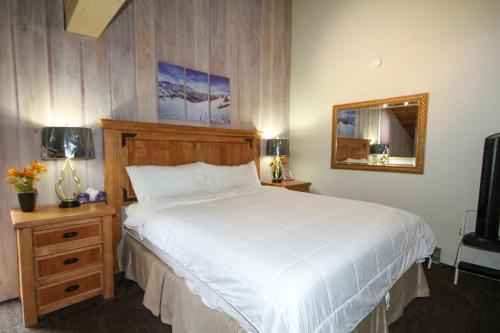 1 dormitorio con 1 cama blanca grande y espejo en Mammoth Ski & Racquet Club #105 - Pet Friendly, en Mammoth Lakes