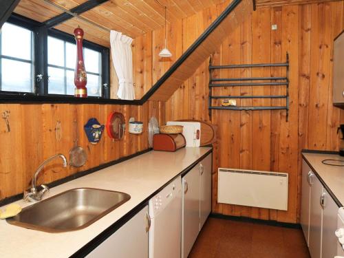 ブラーバンドにあるThree-Bedroom Holiday home in Blåvand 2の木製の壁のキッチン、シンク、カウンターが備わります。