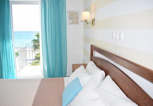 a bedroom with a bed with a view of the ocean at Mirto Beach Hotel & Restaurant in Paralia Vrachou
