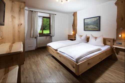 een slaapkamer met een groot bed met witte lakens bij Flinsenlehen in Schönau am Königssee