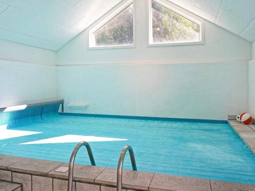 a large swimming pool with blue walls and windows at 12 person holiday home in Aakirkeby in Vester Sømarken