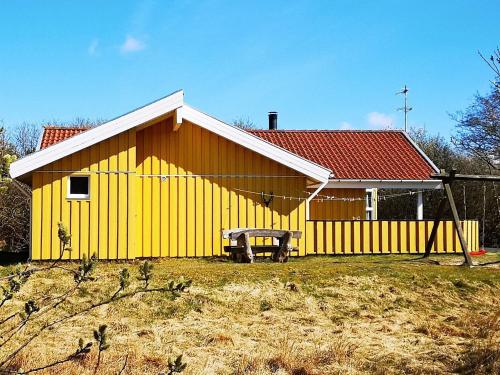 un edificio amarillo con un banco delante de él en 10 person holiday home in Fan en Fanø
