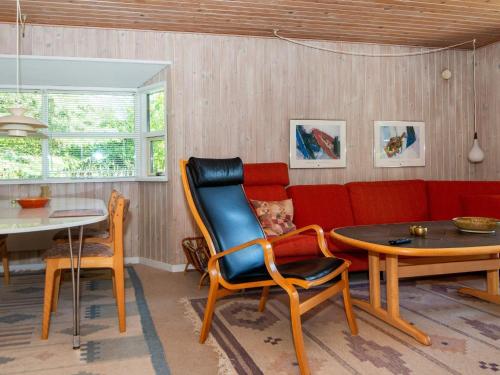 エーベルトフトにある6 person holiday home in Ebeltoftのリビングルーム(赤いソファ、テーブル、椅子付)