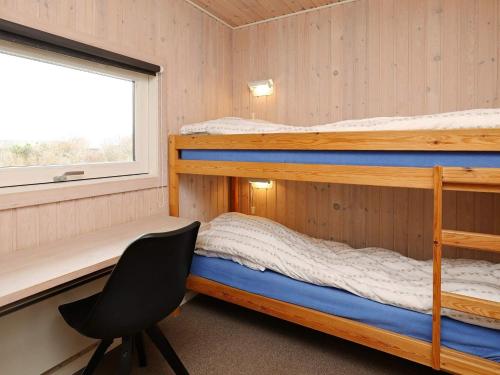 LihmeにあるThree-Bedroom Holiday home in Spøttrup 3の二段ベッド2台と椅子が備わる客室です。