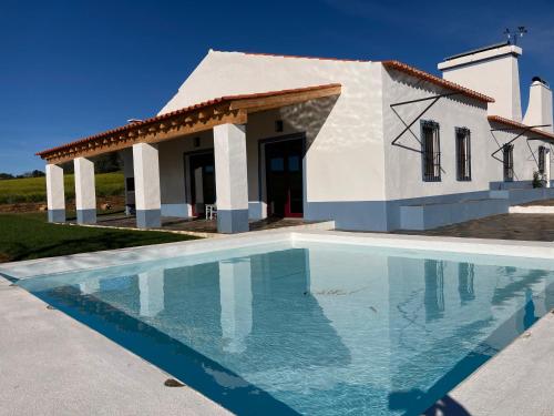 a villa with a swimming pool in front of a house at Monte do Pombal in Sousel