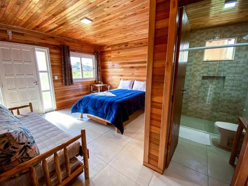 a bedroom with a bed and a shower in a room at Pousada Flor do Campestre in Urubici