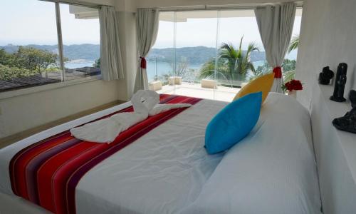 een slaapkamer met een groot bed met een groot raam bij Mexican Condo by the sea in Acapulco