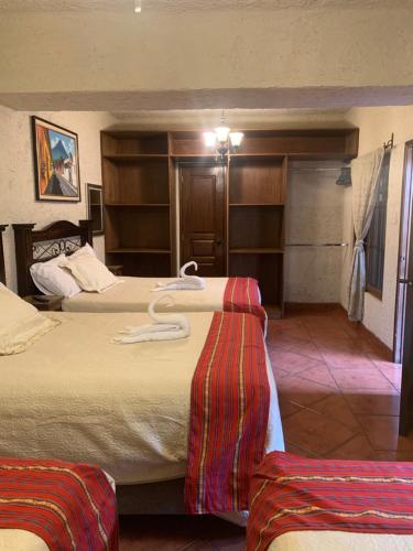 a hotel room with two beds and shelves at Hotel Mansion Del Rey in Antigua Guatemala