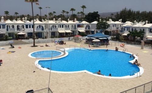 duży basen z ludźmi siedzącymi wokół niego w obiekcie Bungalow Playmar Maspalomas w mieście Maspalomas