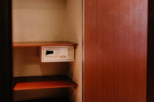 a small kitchen with a microwave on a shelf at Hotel Santamaria in Guarujá