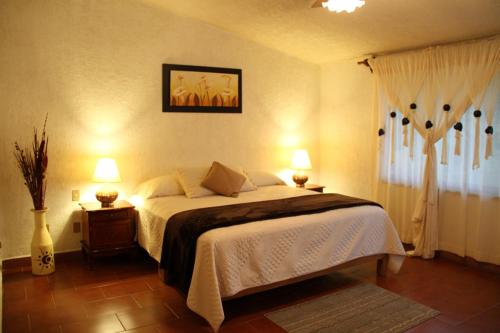 een slaapkamer met een groot bed en 2 lampen bij Hotel Quinta del Sol in Tepoztlán