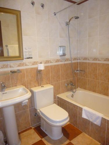 a bathroom with a toilet and a sink and a tub at Hotel Leku Eder in Donostia-San Sebastián