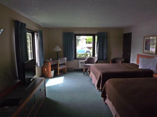 a hotel room with two beds and a flat screen tv at Travelodge by Wyndham Kalispell in Kalispell