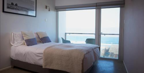 a bedroom with a bed and a large window at Pichilemu Surf Hotel in Pichilemu