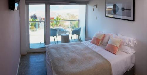 a bedroom with a bed with a view of a balcony at Pichilemu Surf Hotel in Pichilemu